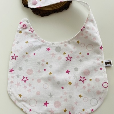 Babete branco com padrão de estrelas e círculos coloridos e fecho rosa