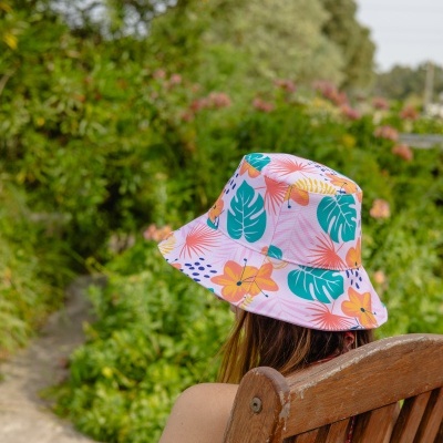Chapéu floral colorido tipo pescador numa pessoa sentada numa cadeira de madeira ao ar livre