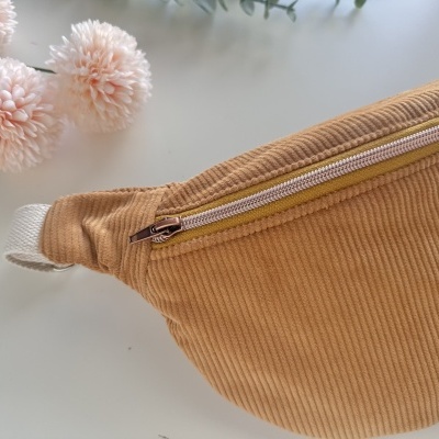 Necessaire caramelo com fecho dourado sobre fundo branco com flores cor-de-rosa