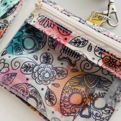 Bolsa pequena com padrão colorido de caveiras e flores