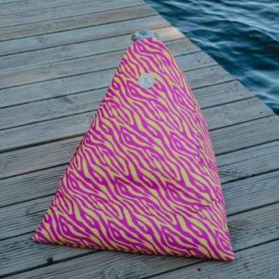 Almofada triangular rosa e amarela com padrão de riscas num cais perto da água