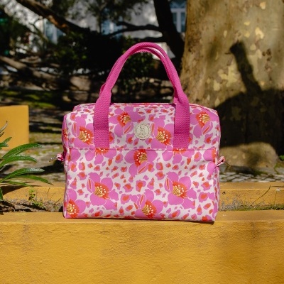 Mala rosa com padrão floral colocada sobre estrutura amarela ao ar livre