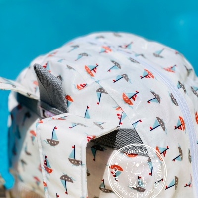 Mochila branca com padrão colorido de guarda-chuvas junto a piscina azul