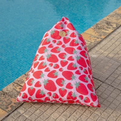 Almofada triangular com padrão de morangos vermelhos junto à piscina