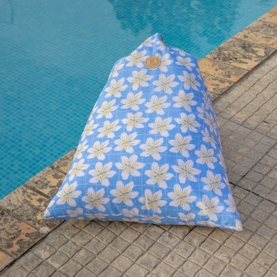 Almofada triangular azul com flores brancas e amarelas junto a piscina