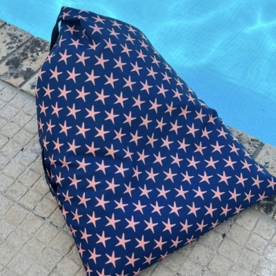 Pufe azul escuro com estrelas cor-de-rosa junto a uma piscina.