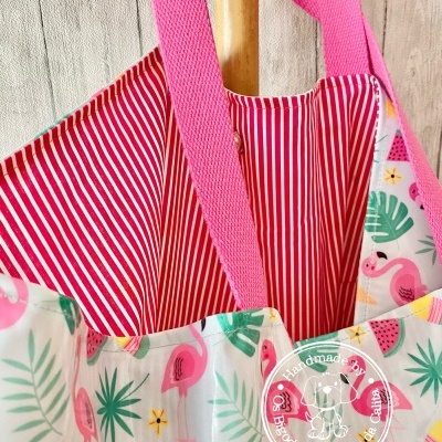 Mala colorida com padrão de flamingos e frutas, interior riscado e alças cor-de-rosa