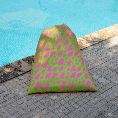 Puff triangular verde com manchas rosa junto a piscina
