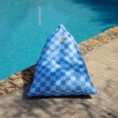 Pouf azul e branco com padrão xadrez junto a piscina