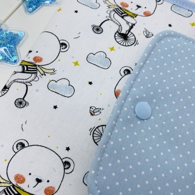 Capa de tecido branco com ursos e bolso azul claro com bolinhas brancas