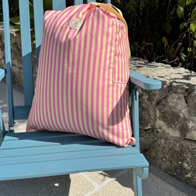 Mochila riscada rosa e amarelo numa cadeira azul ao ar livre
