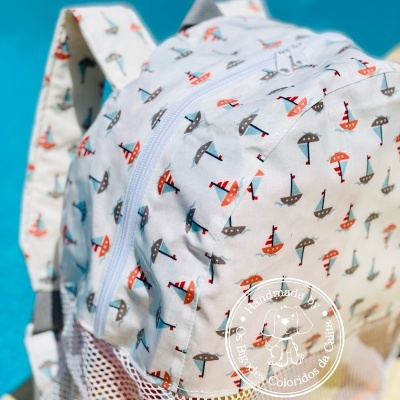 Mochila branca com padrão de barcos coloridos junto a piscina
