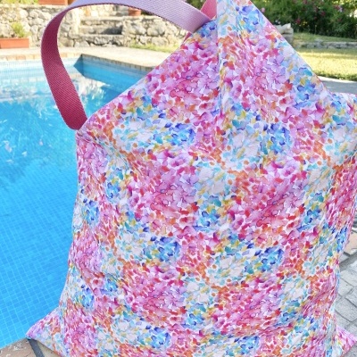 Mala de pano floral multicolorida junto a piscina