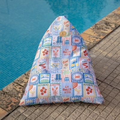Puff triangular colorido junto à piscina com padrão de azulejos e textos em inglês e italiano.