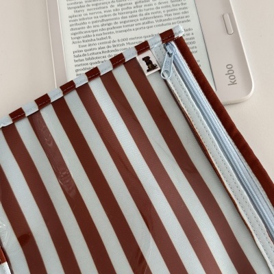 Leitor digital Kobo branco com capa transparente e bolsa riscada castanha e branca com fecho azul