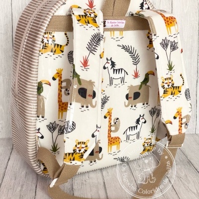 Mochila infantil com padrão de animais em fundo creme e riscas bejes nas costas