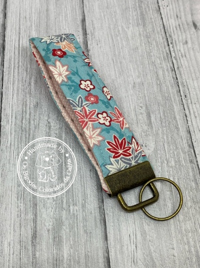 Chaveiro em tecido azul com padrão de folhas e metal bronze