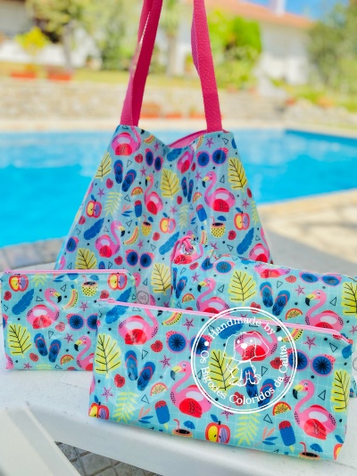 Conjunto de saco e bolsas com padrão de flamingos, frutas e folhas, junto a piscina.