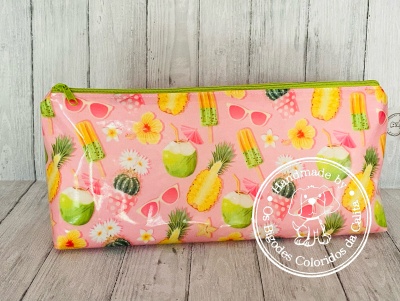 Estojo retangular com padrão colorido de frutas tropicais e óculos em fundo rosa.