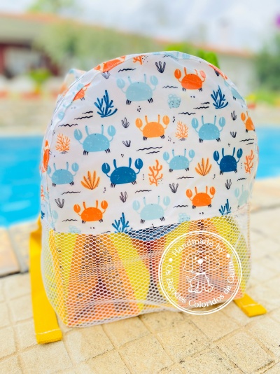 Mochila branca com padrão colorido de caranguejos e bolso frontal em rede
