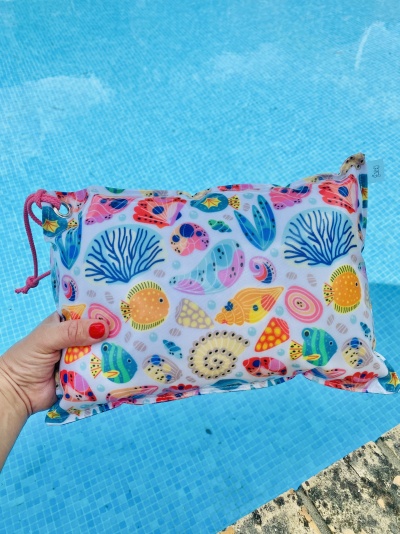 Necessaire colorida com padrão de peixes e conchas perto de piscina