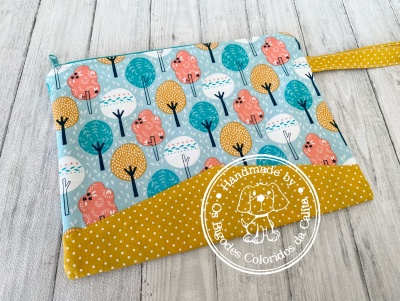 Necessaire retangular colorida com padrão de árvores e pássaros em fundo azul claro e faixa amarela com pontos brancos