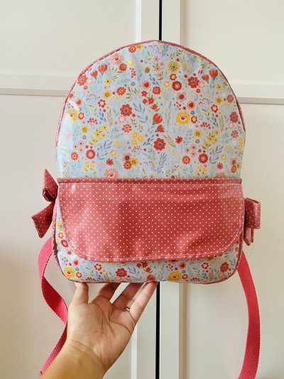 Mochila infantil com padrão floral colorido e rosa com bolinhas em fundo branco