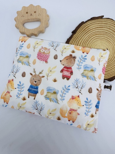 Almofada estampada com animais e mordedor de madeira em formato de flor ao lado