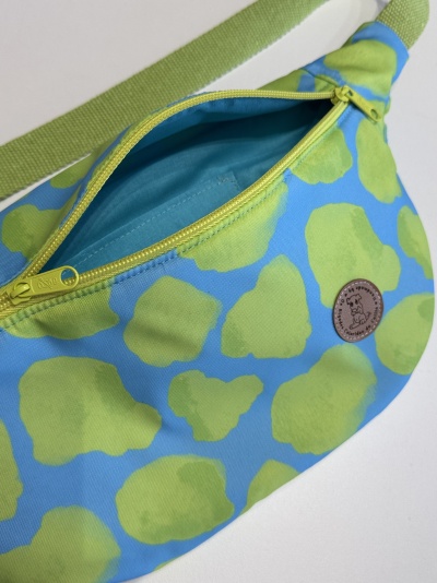Bolsa tipo pochete com padrão azul e verde e fecho amarelo