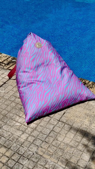Pufe triangular rosa e lilás junto a piscina