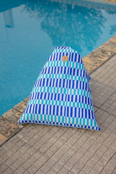 Saco de almofada com padrão de riscas azul, branco e verde ao lado de uma piscina.