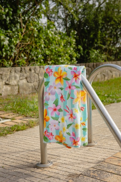 Toalha de tecido floral colorida pendurada em estrutura metálica ao ar livre