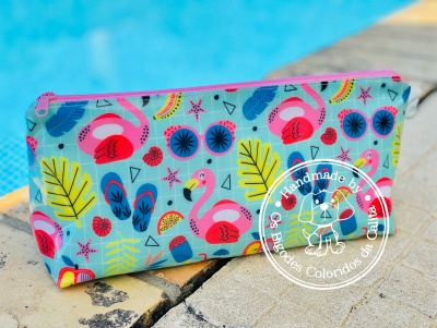 Necessaire com padrão de flamingos, folhas e óculos de sol junto a piscina