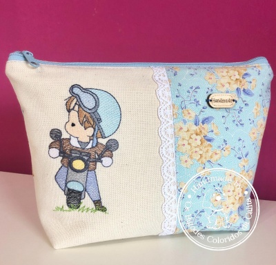 Necessaire de tecido com desenho bordado de criança numa motorizada e tecido floral azul com flores amarelas