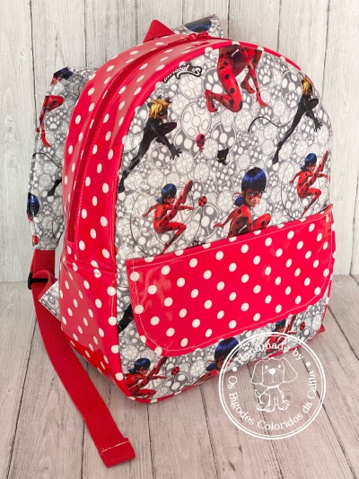 Mochila colorida com personagens femininas e padrão de bolinhas brancas