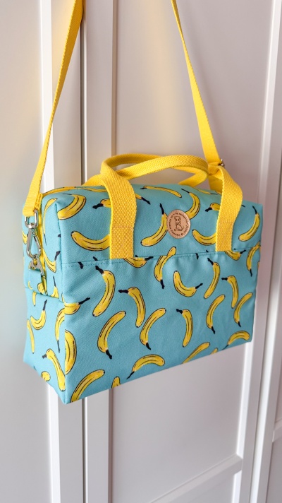 Mala azul com padrão de bananas e alças amarelas