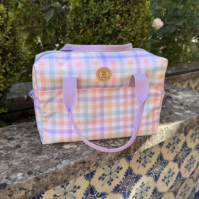 Mala xadrez em tons pastel com alças lilás sobre pedra decorada com azulejos