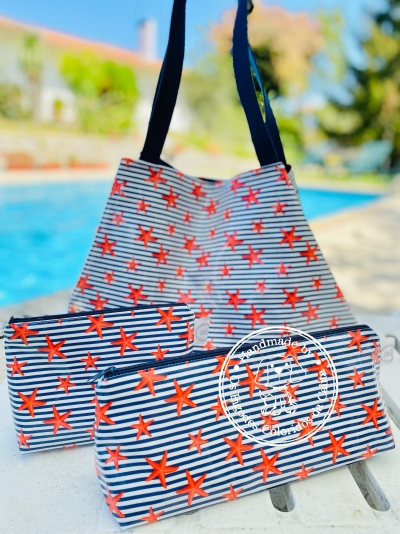 Bolsa e duas necessaires com padrão de riscas azuis e brancas e estrelas vermelhas junto à piscina