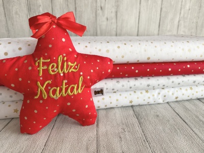 Estrela vermelha de tecido com a frase Feliz Natal e rolos de tecido com padrões de bolinhas douradas