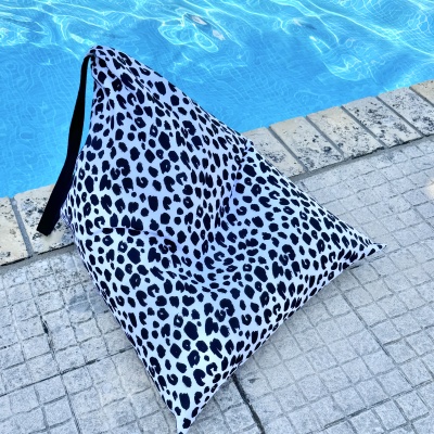 Puff triangular preto e branco junto a piscina