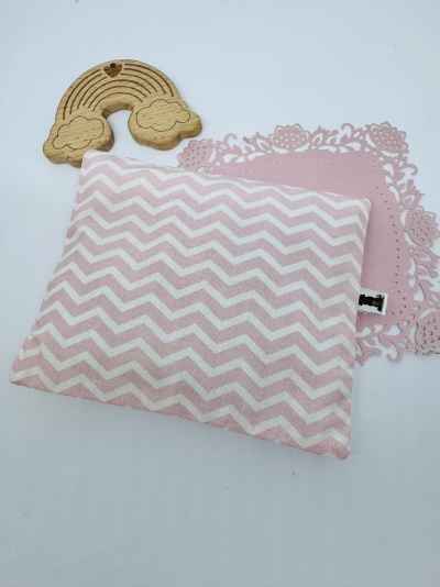 Almofada rosa e branca com padrão chevron junto a enfeite de madeira em forma de arco-íris