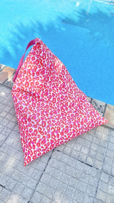 Pufe triangular em tecido estampado junto a piscina