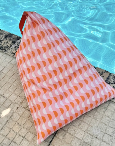 Almofada triangular rosa e laranja junto a piscina