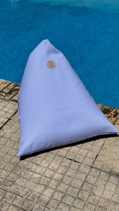 Puff triangular azul e branco ao lado de piscina