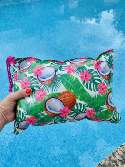 Mala de tecido colorida com padrão tropical segurada junto a piscina