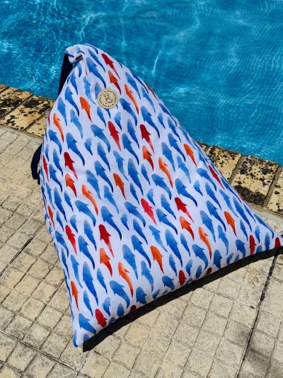 Puff triangular com padrão de peixes coloridos junto a piscina