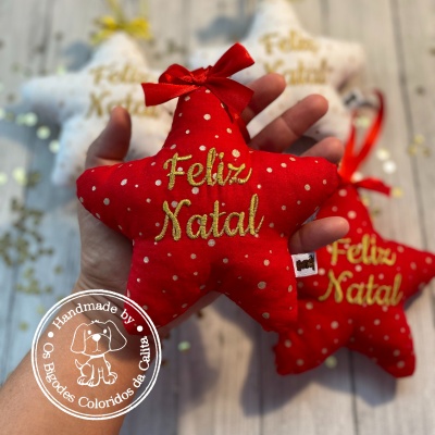 Estrela de tecido vermelha com pontos brancos e texto 'Feliz Natal' bordado em amarelo
