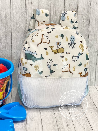 Mochila infantil com padrão de animais marinhos e parte inferior em rede branca