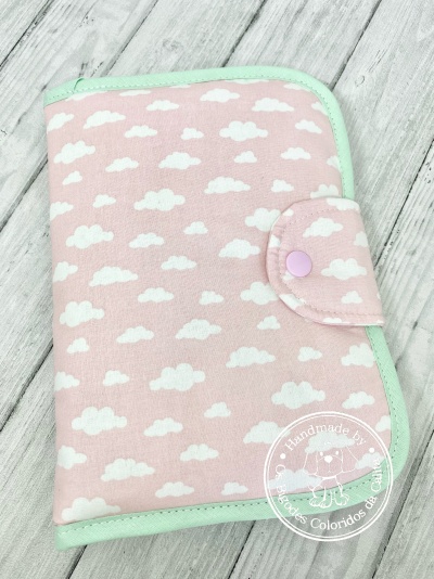 Capa cor-de-rosa com nuvens brancas, bordas verdes e botão de pressão rosa