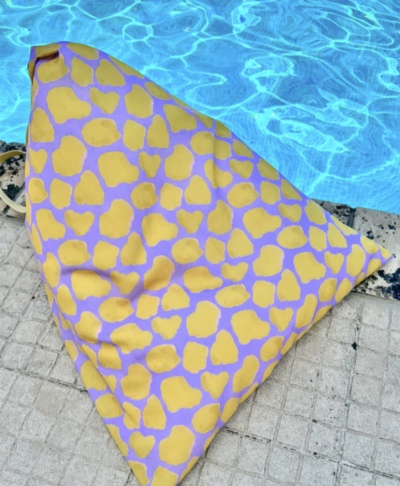 Almofada triangular amarela e roxa ao lado de piscina